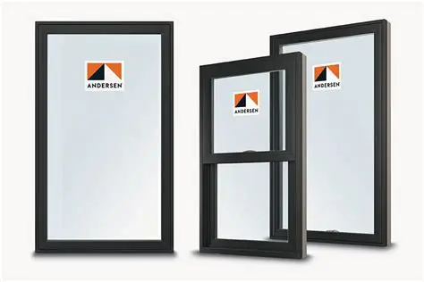 Gemini said Three black-framed Andersen windows are displayed against a clean, white background. On the left is a large, fixed picture window, while the right features a double-hung window standing slightly in front of another large picture window. Each window pane displays the orange and black Andersen logo sticker. The image has a professional, studio-shot quality with soft shadows at the base.