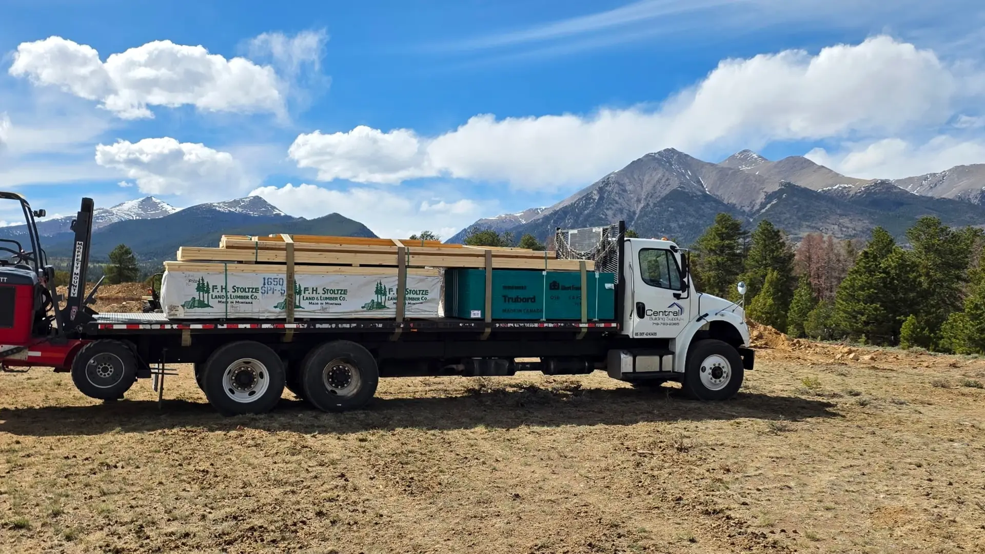Central Building Supply flatbed carrying lumber beneath the Sangre de Cristo Mountains