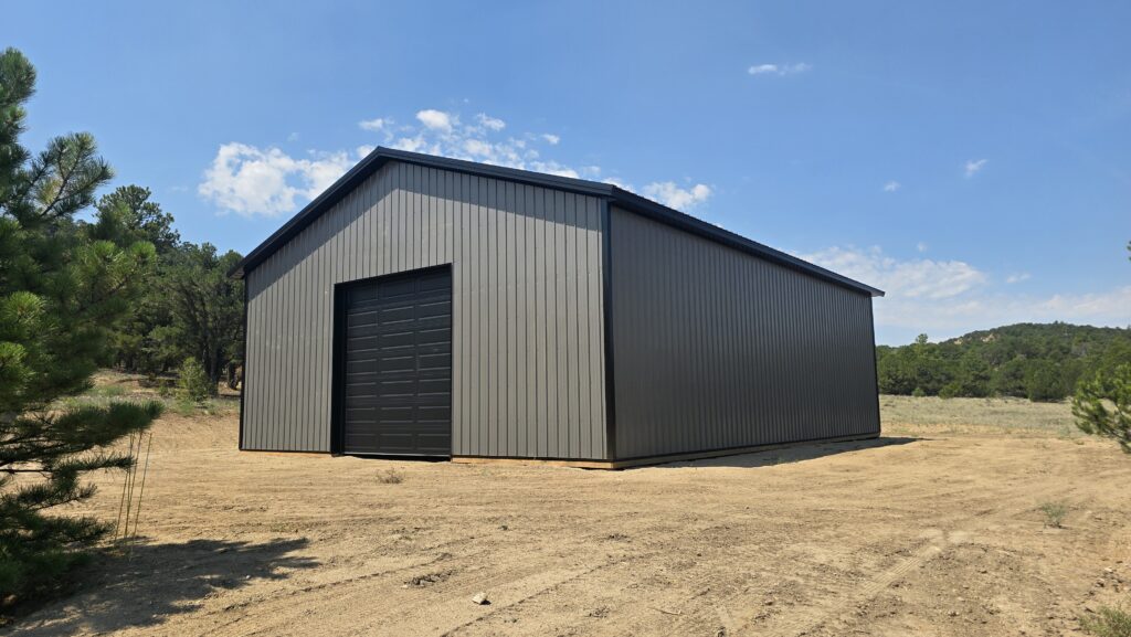 Ground-level view of a black 12x12 CHI overhead door, charcoal siding and black trim on a Colorado storage building