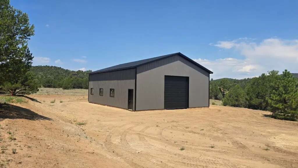 Ground-level view of a 36x48 charcoal storage building with black roof, trim, walk-in door and windows in Cotopaxi, Colorado