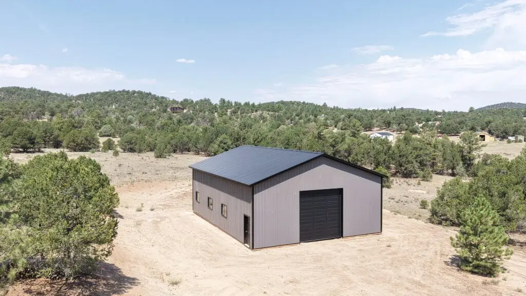 Aerial front and side view of a 36x48 charcoal storage building with a black roof, garage door, walk-in door and windows in Cotopaxi, Colorado